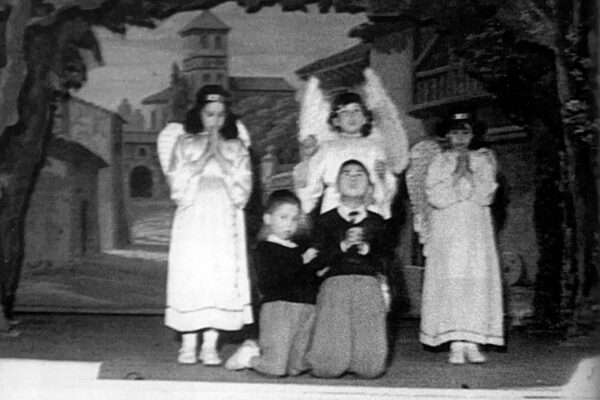 Arrodillado, a la izquierda, en una obra de teatro de su colegio.